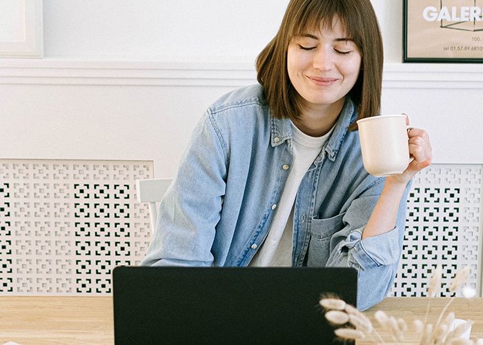Woman Drinking Coffee Happily at Laptop