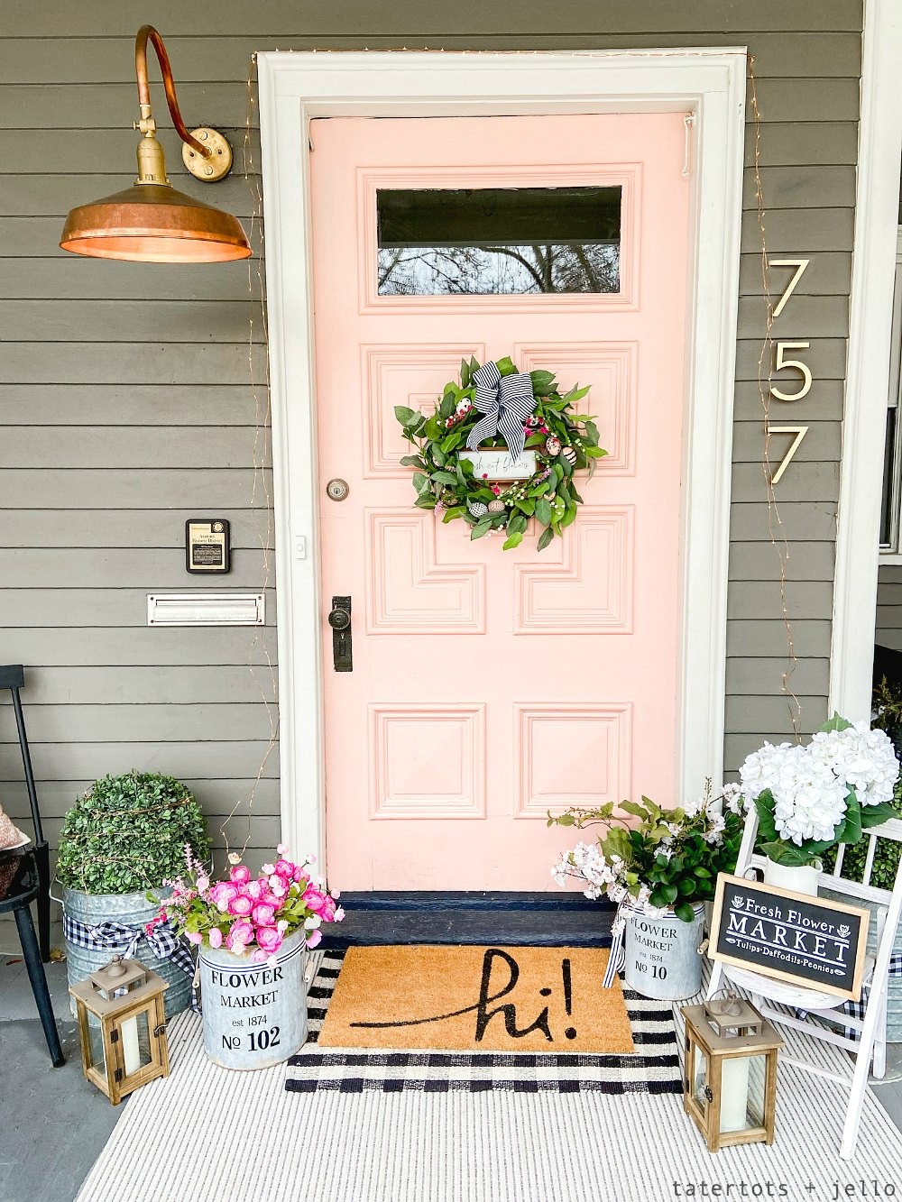 A peachy pink front door and potted plants on porch