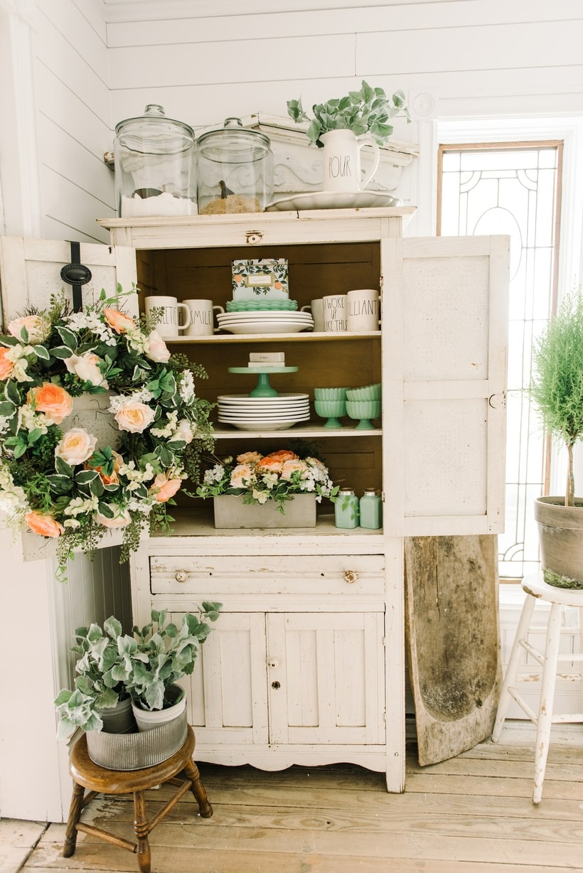 Farmhouse hutch with mint dishes and floral wreath