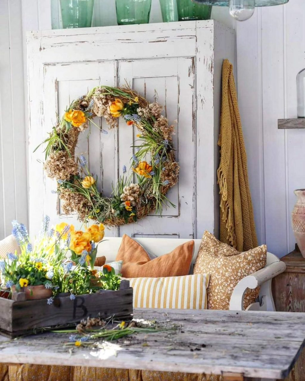 a wildflower wreath hanging on a farmhouse armoire